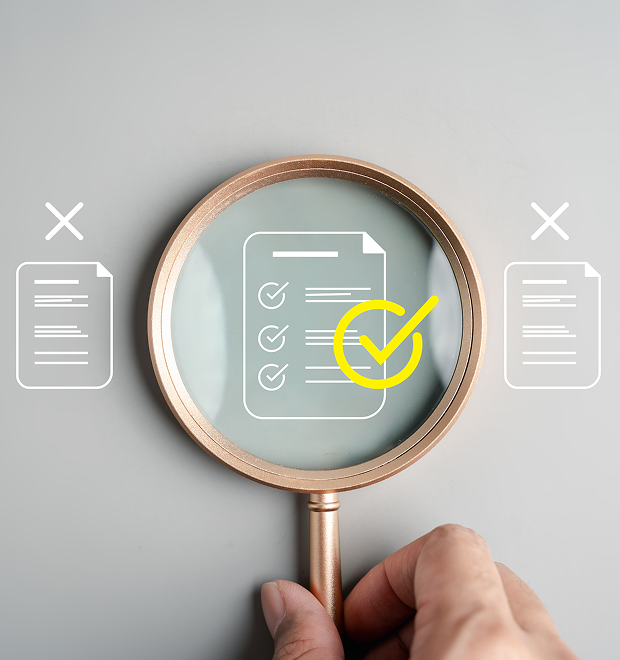 A hand holds a magnifying glass over a checklist document with a yellow check mark, flanked by two crossed-out document icons.