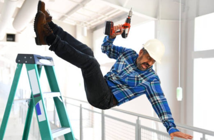 Worker falling off ladder with drill.